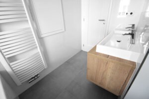 Koupelna s dřevěnými doplňky a šedou dlažbou